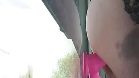 Horny girl sucks dildo on a window